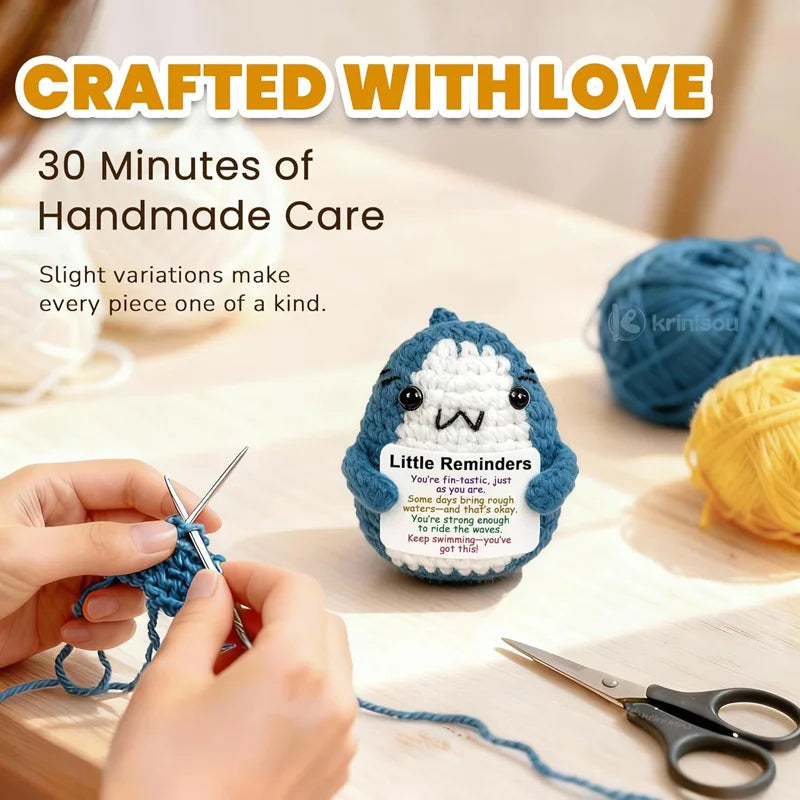 Handmade crocheted shark with motivational quote, surrounded by yarn and knitting tools