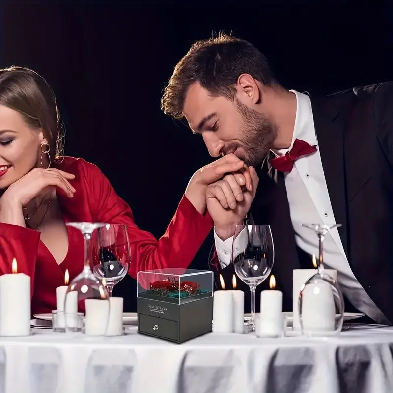 Romantic dinner setup with candles, wine glasses, and a gift box for couples
