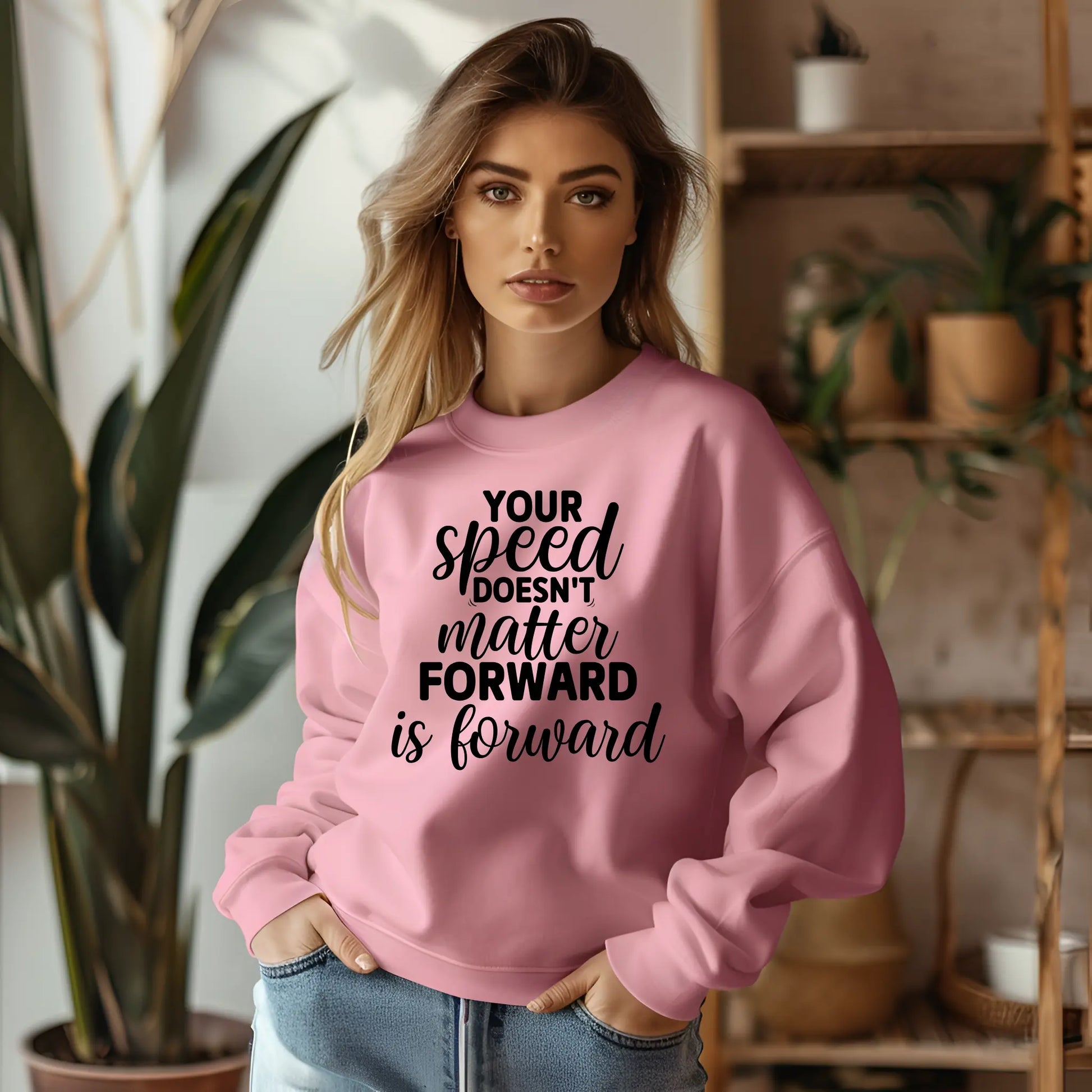 Woman wearing a pink sweatshirt with motivational text in a home setting