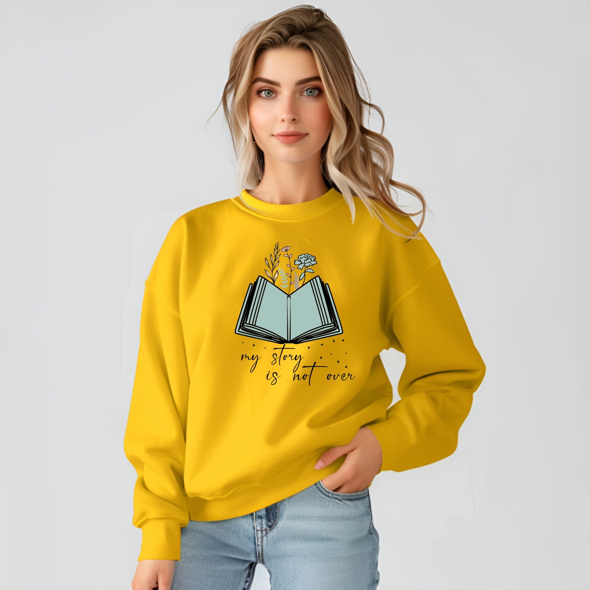 Woman wearing a yellow sweatshirt with a book design and text on a plain background