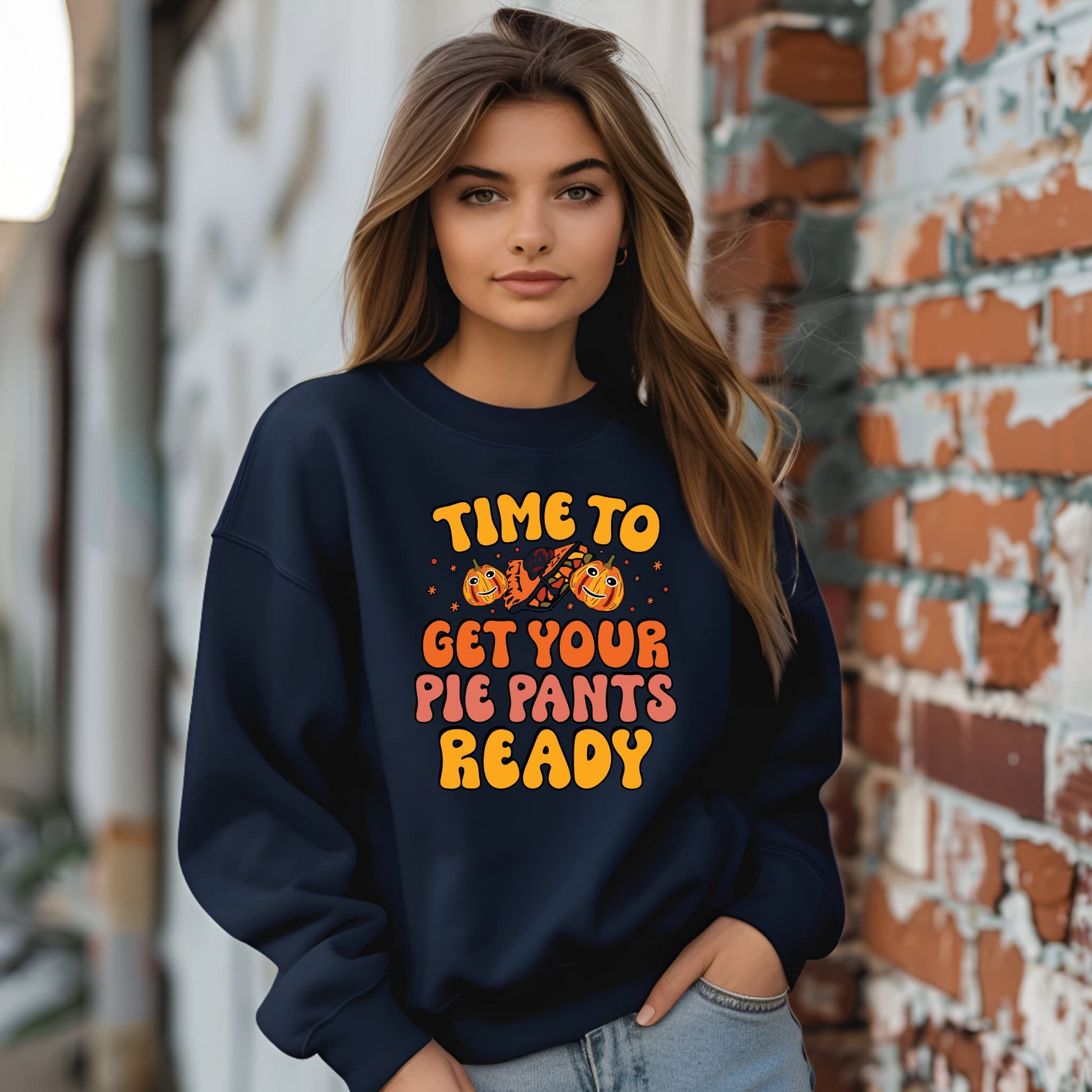 Woman wearing a navy sweatshirt with Halloween-themed text, standing against a brick wall.