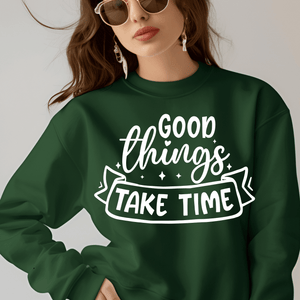 Person wearing a green sweatshirt with 'Good things take time' text on a plain background
