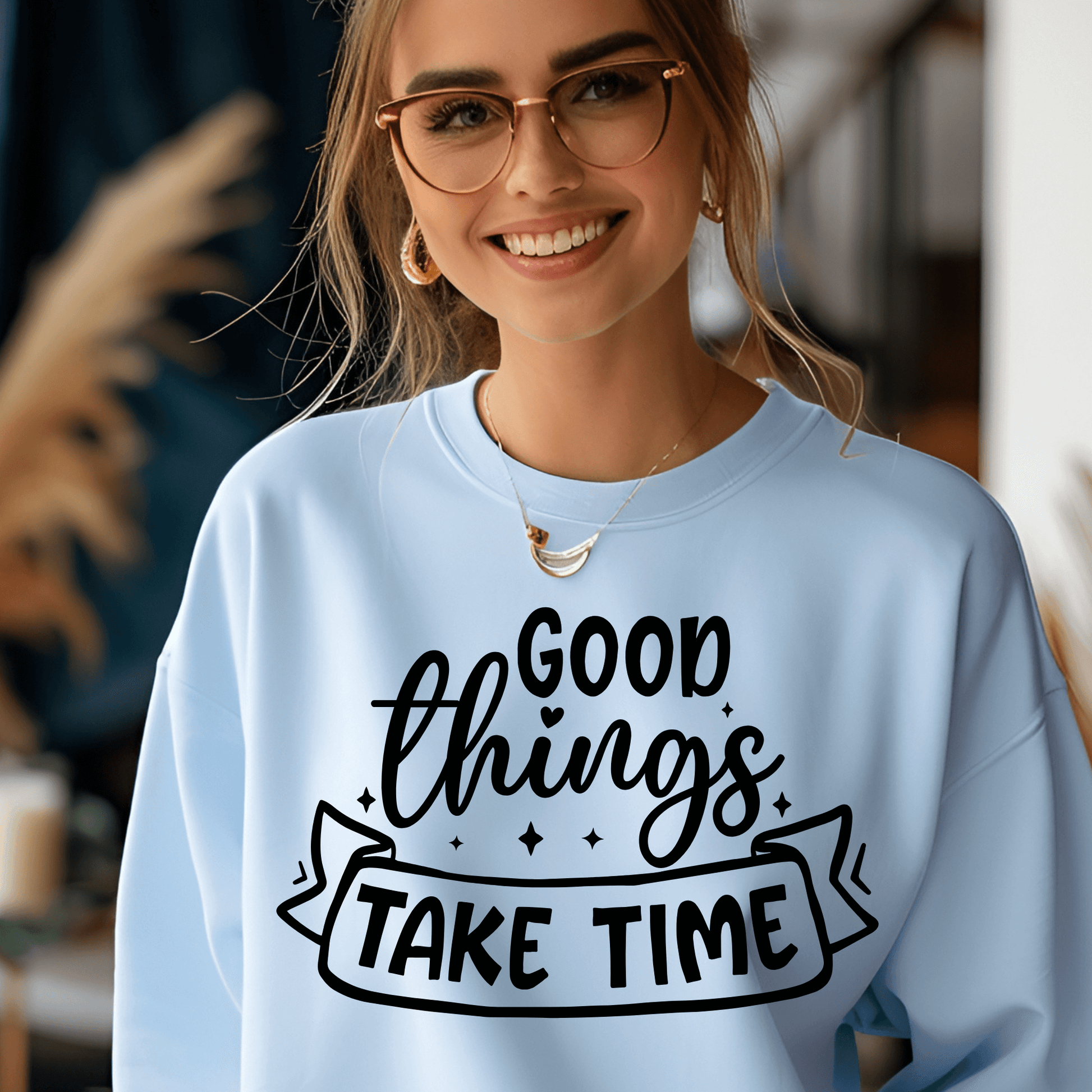 Woman wearing a light blue sweatshirt with 'Good things take time' text.