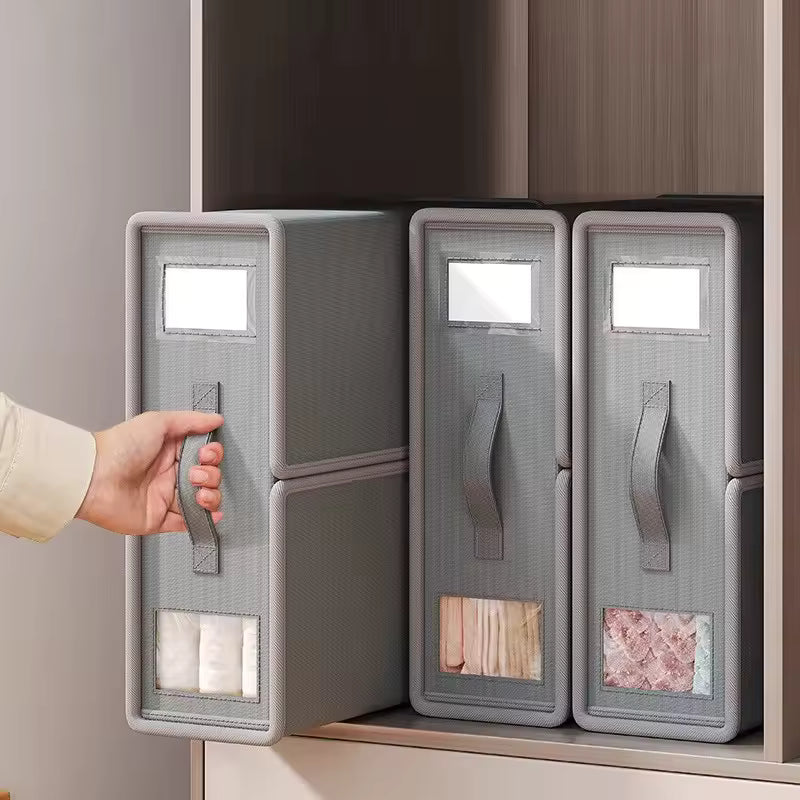 Gray storage boxes with handles on a shelf, one being opened by a hand.
