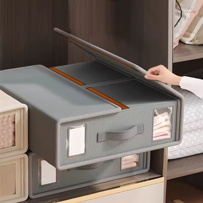 Gray storage box with transparent lid being opened on a wooden shelf.