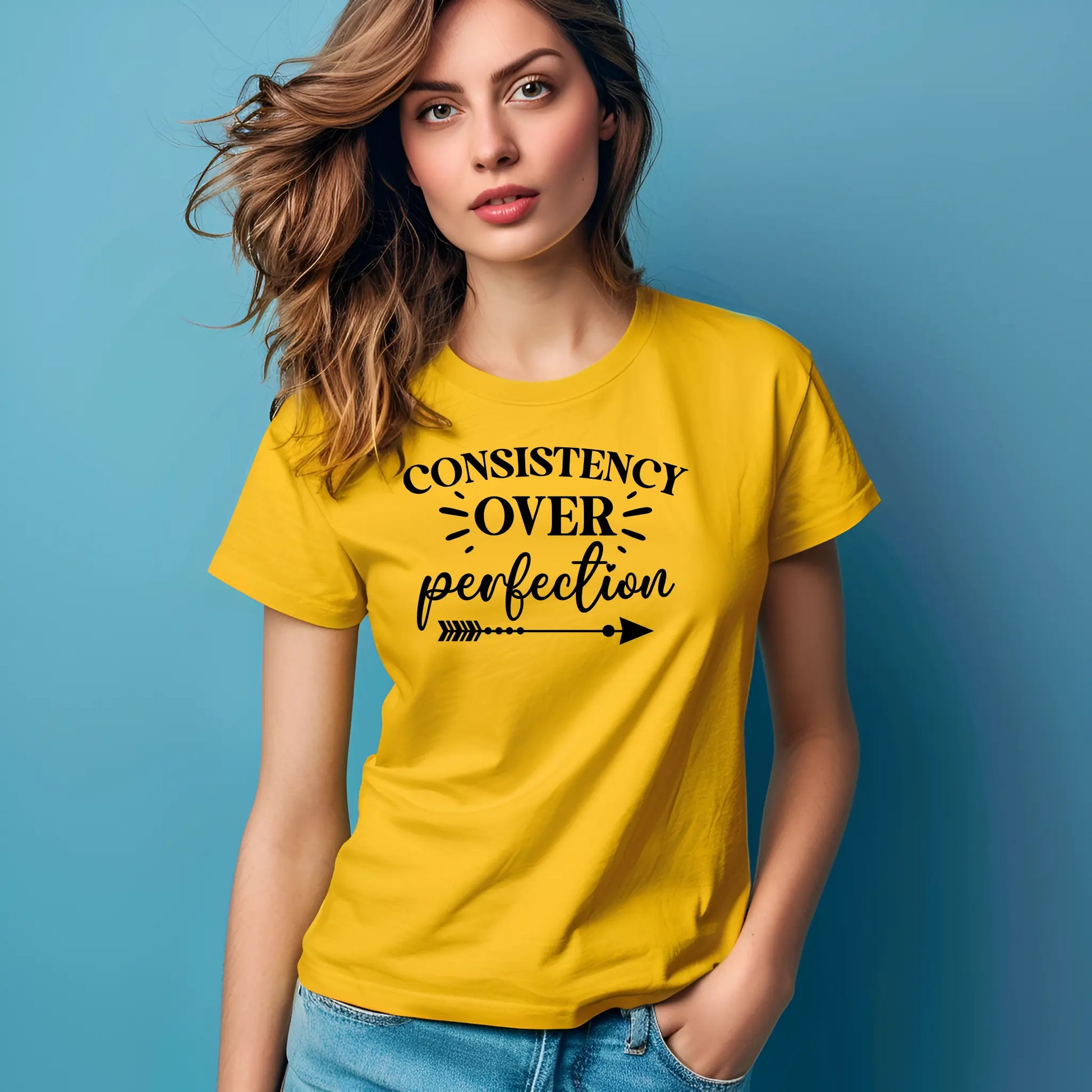 Woman wearing a yellow t-shirt with 'Consistency over perfection' text on a blue background