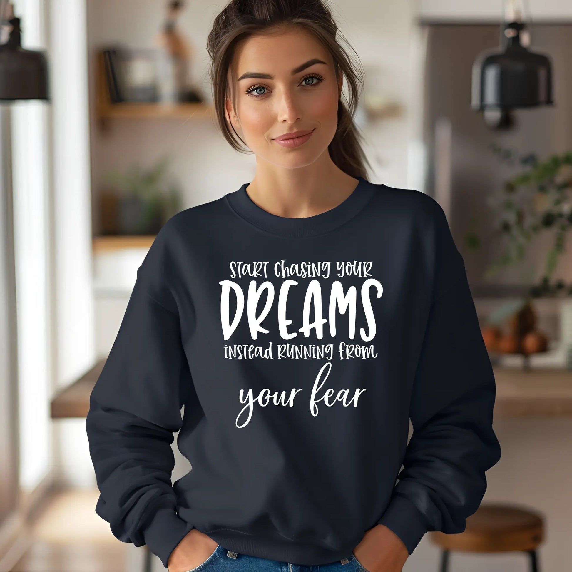 Woman wearing a navy blue sweatshirt with motivational quote in a blurred indoor setting