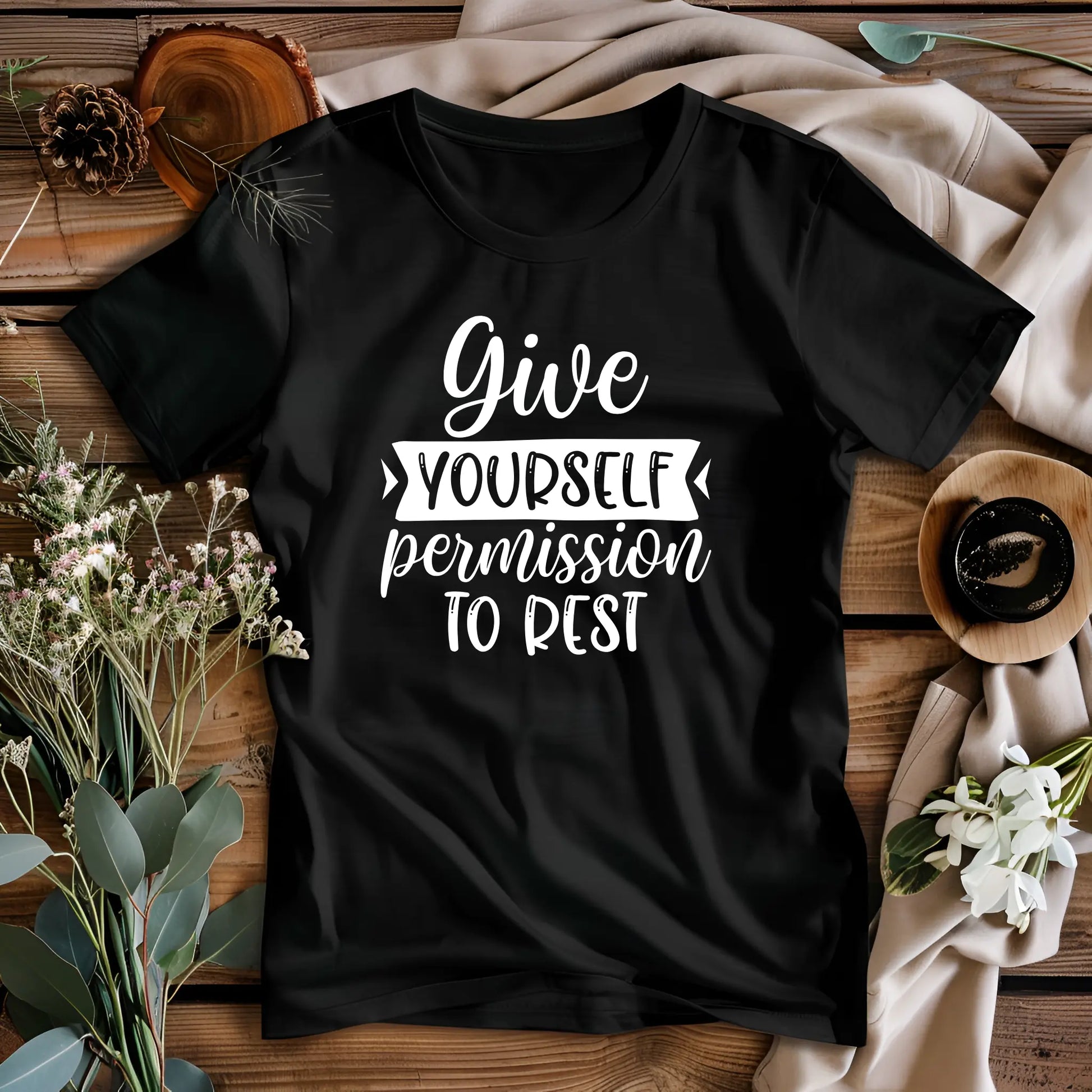 Black t-shirt with motivational quote on a wooden surface with decorative elements
