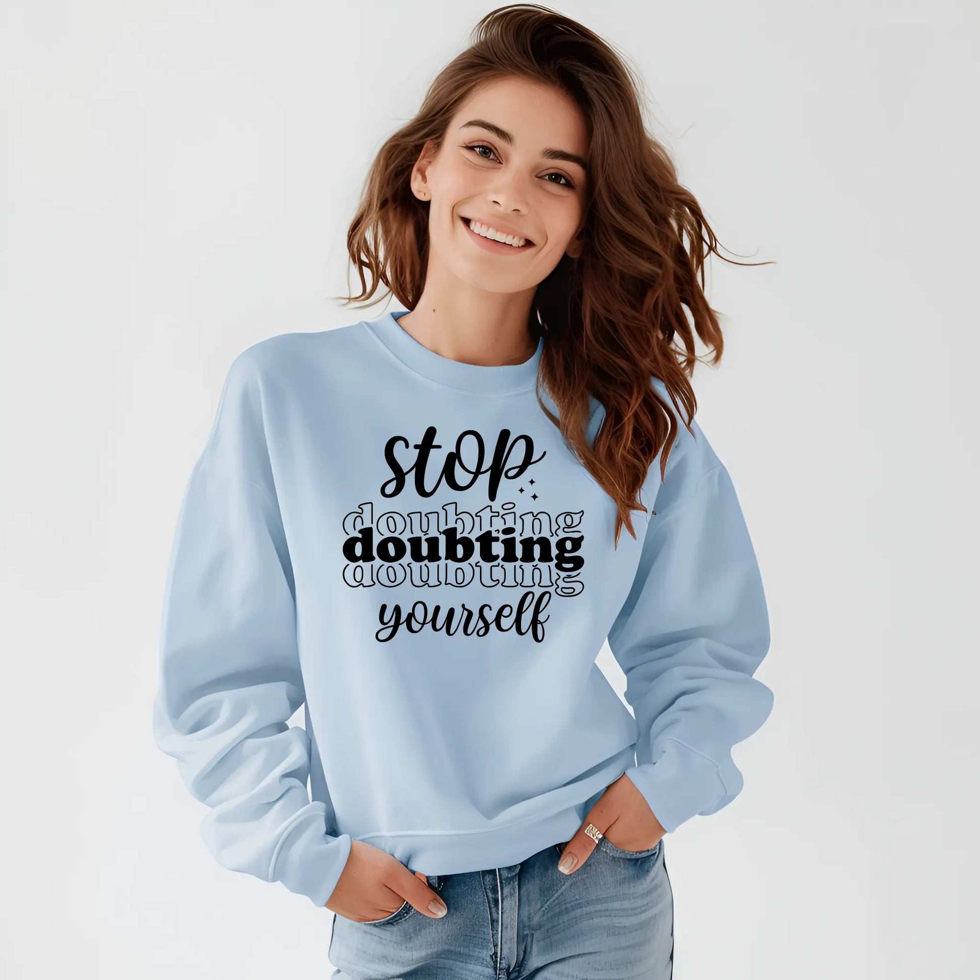 Woman wearing a light blue sweatshirt with motivational text on a white background
