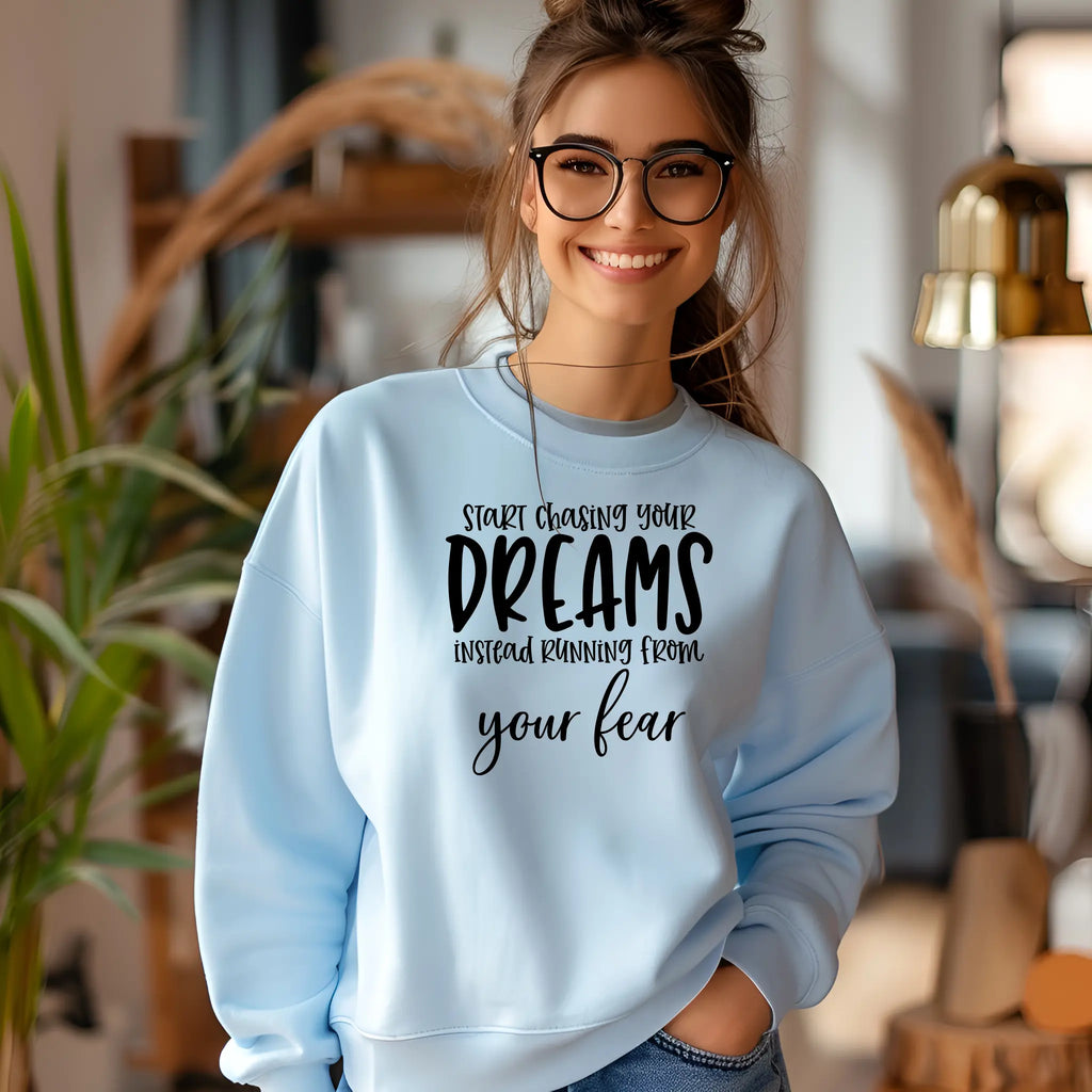 Woman wearing a light blue sweatshirt with motivational text in a home setting