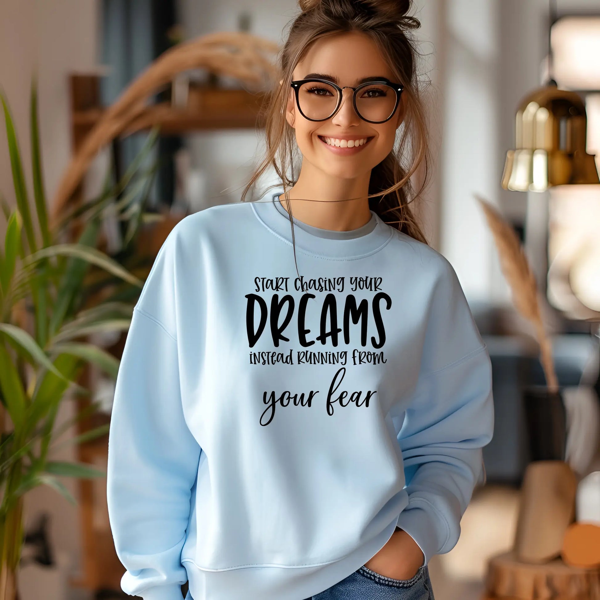 Woman wearing a light blue sweatshirt with motivational text in a home setting
