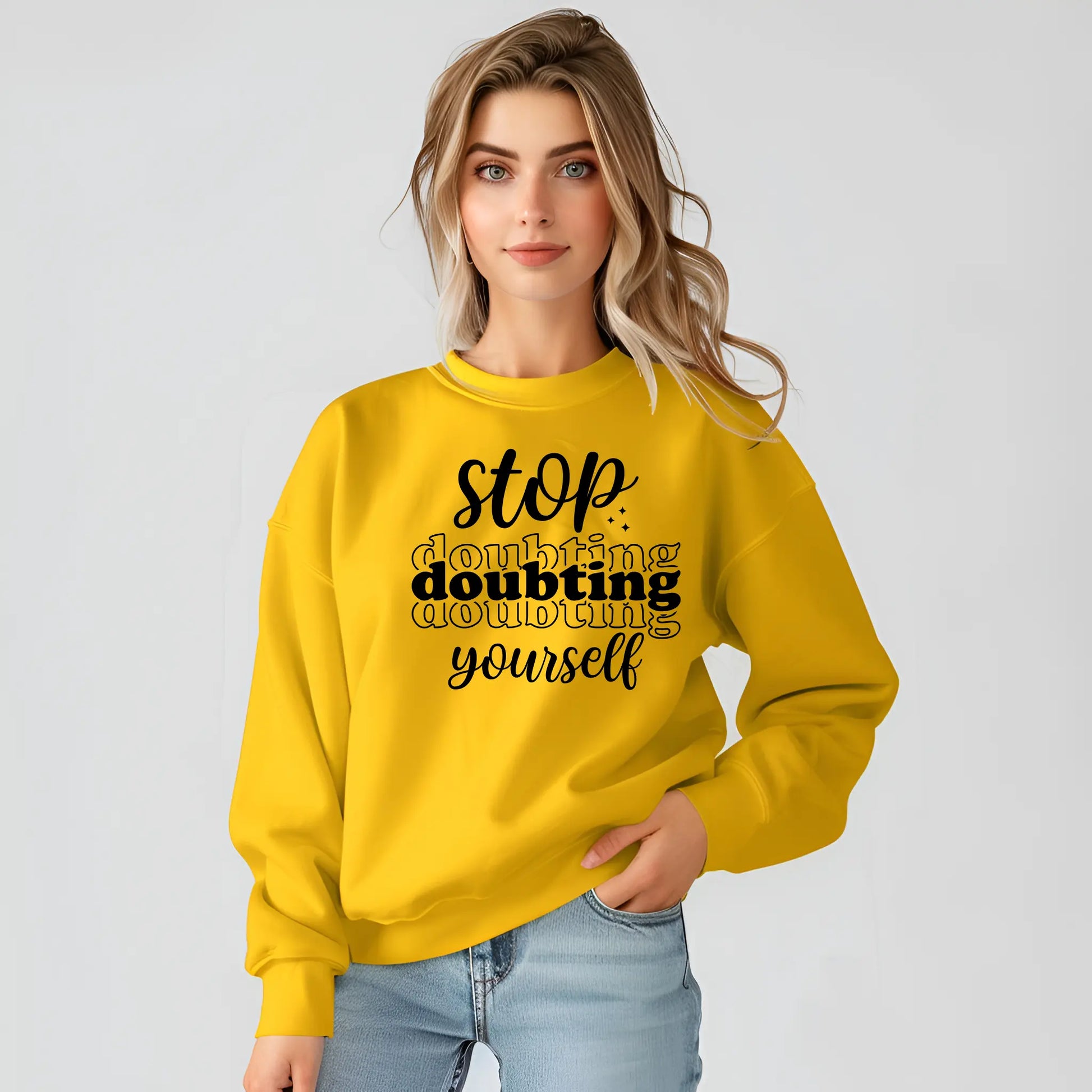 Woman wearing a yellow sweatshirt with motivational text on a plain background