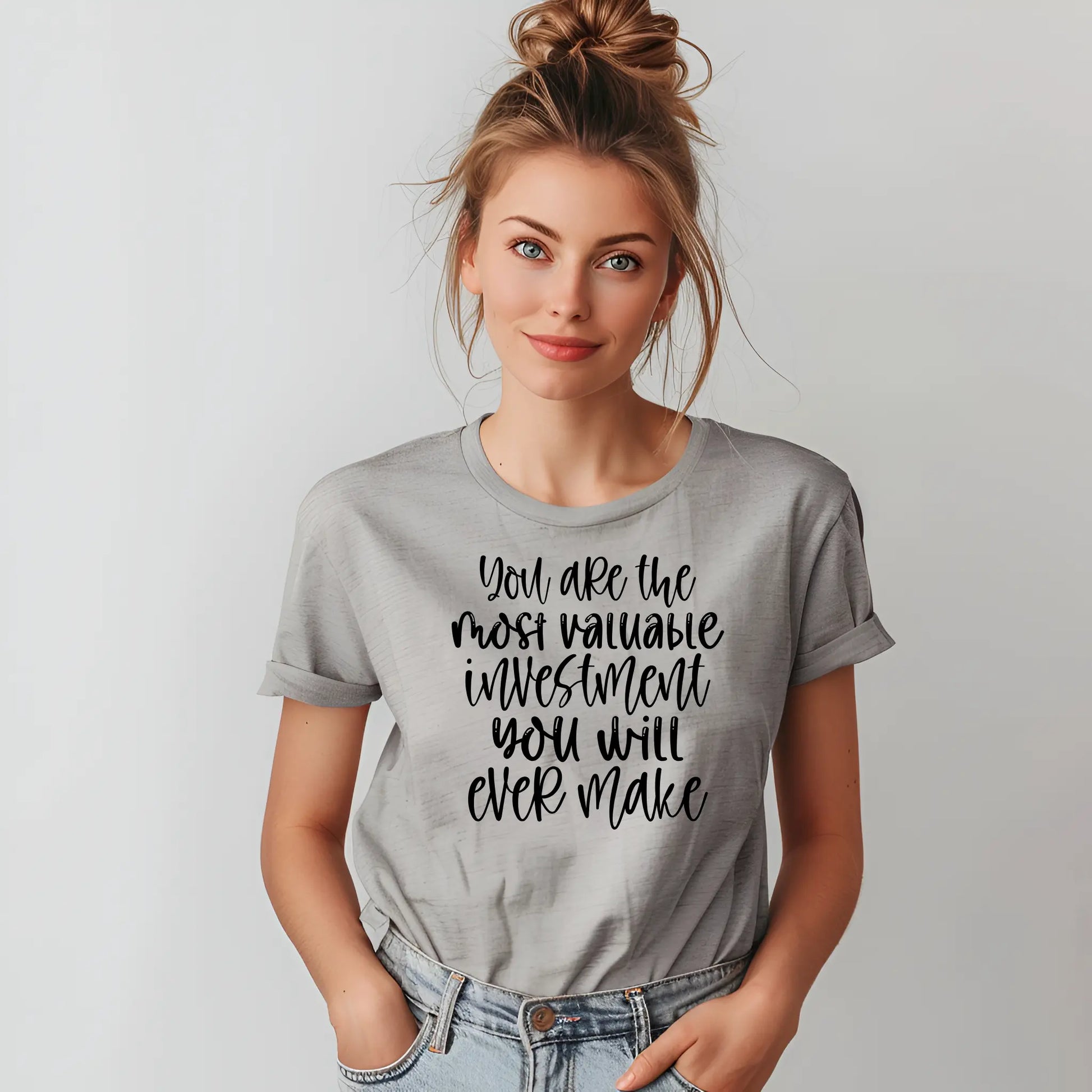 Woman wearing a gray t-shirt with motivational quote on a plain background