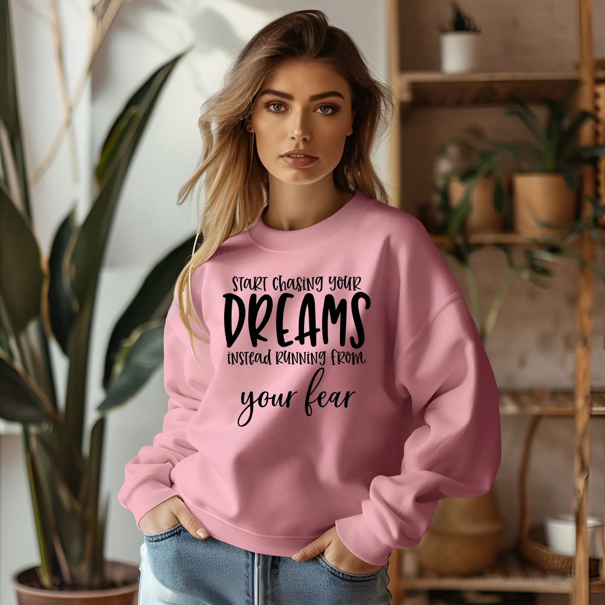 Woman wearing a pink sweatshirt with motivational text in a home setting