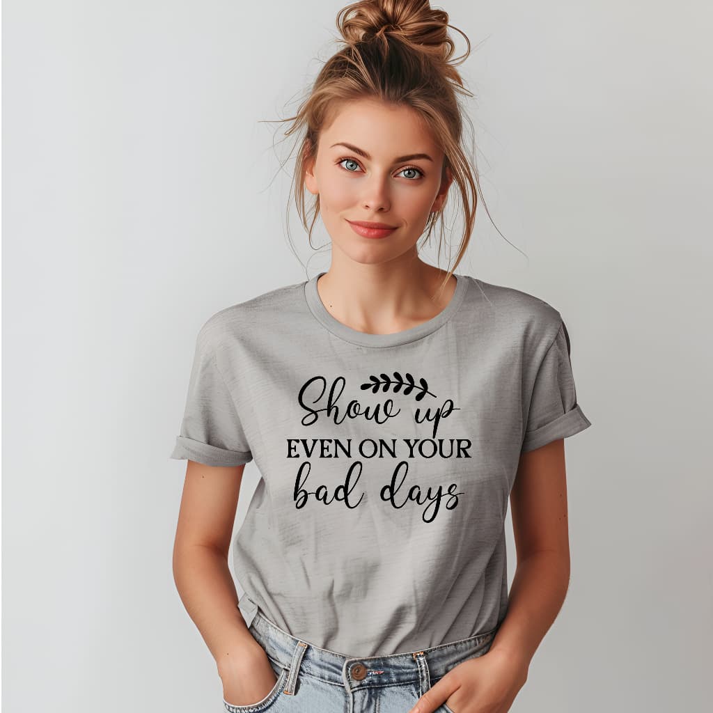 Woman wearing a gray t-shirt with motivational text on a plain background