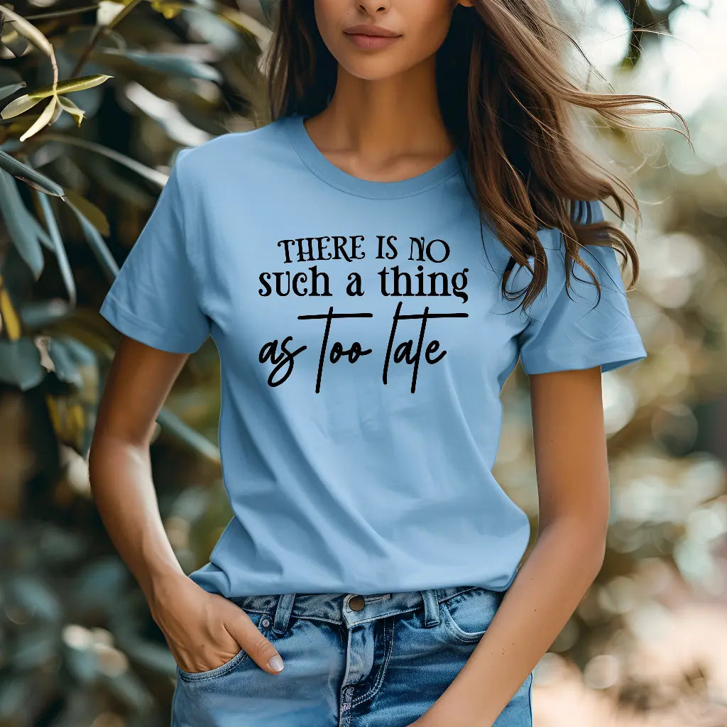 Person wearing a light blue t-shirt with motivational text against a blurred natural background