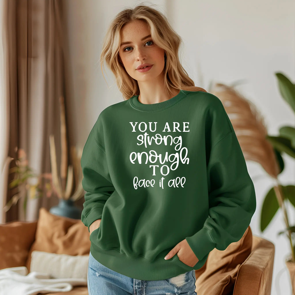 Woman wearing a green sweatshirt with motivational text in a cozy indoor setting