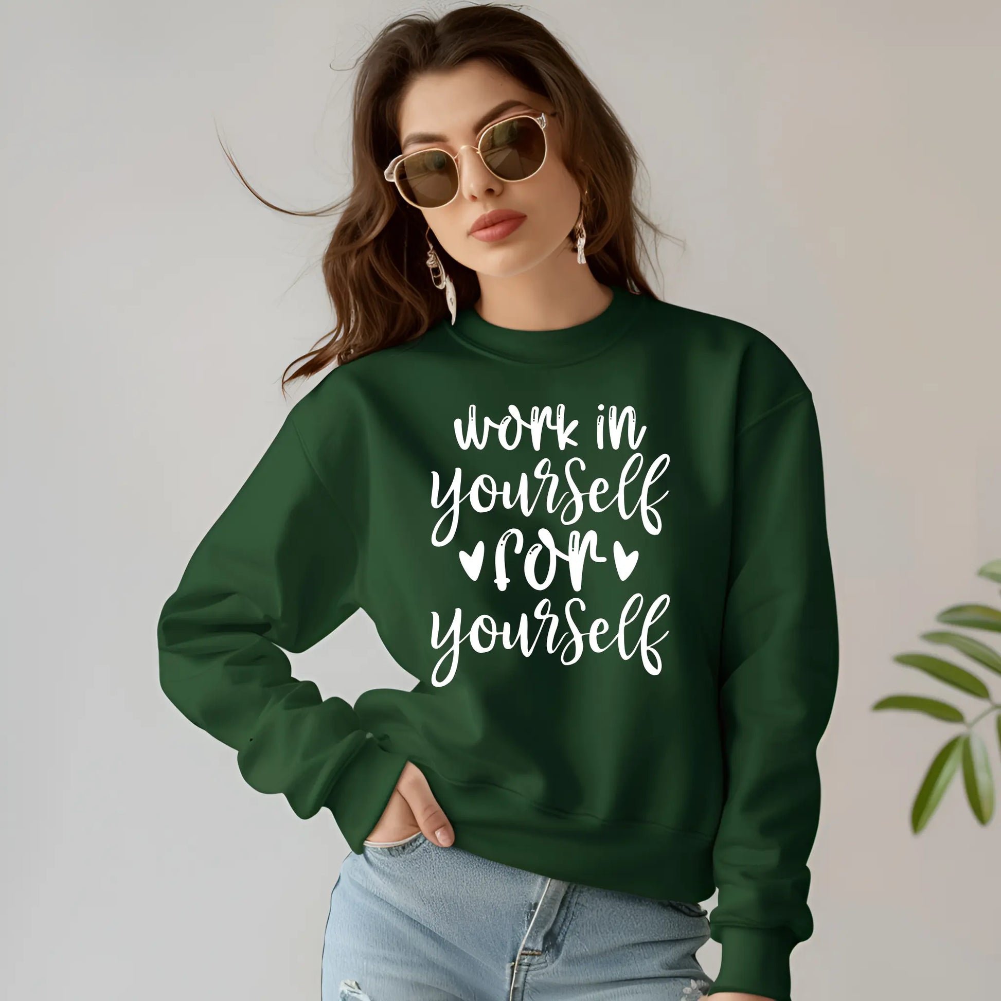 Woman wearing a green sweatshirt with motivational text, standing against a plain background.