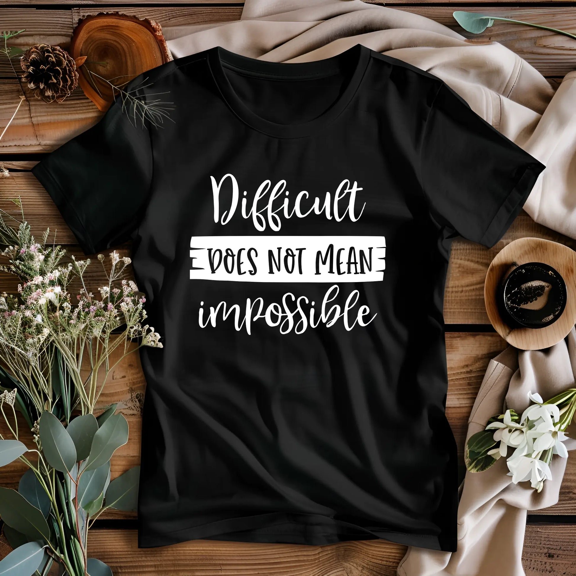 Black t-shirt with motivational quote on a wooden surface with decorative elements