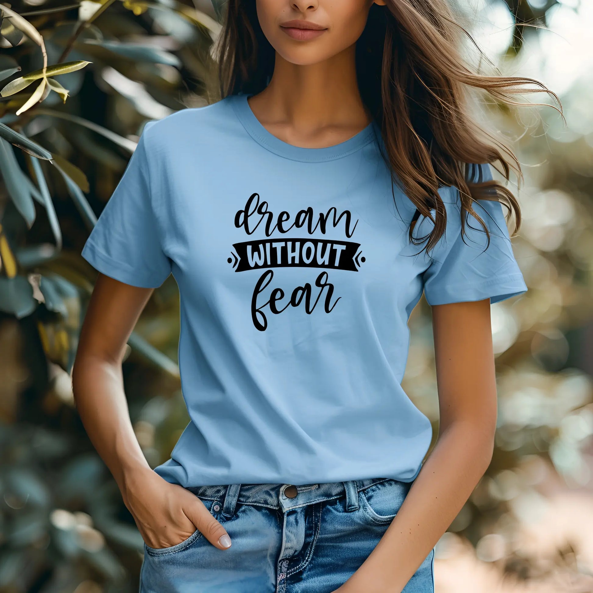 Person wearing a light blue t-shirt with 'dream without fear' text in a natural setting
