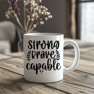 White mug with 'Strong Brave Capable' text on a wooden table