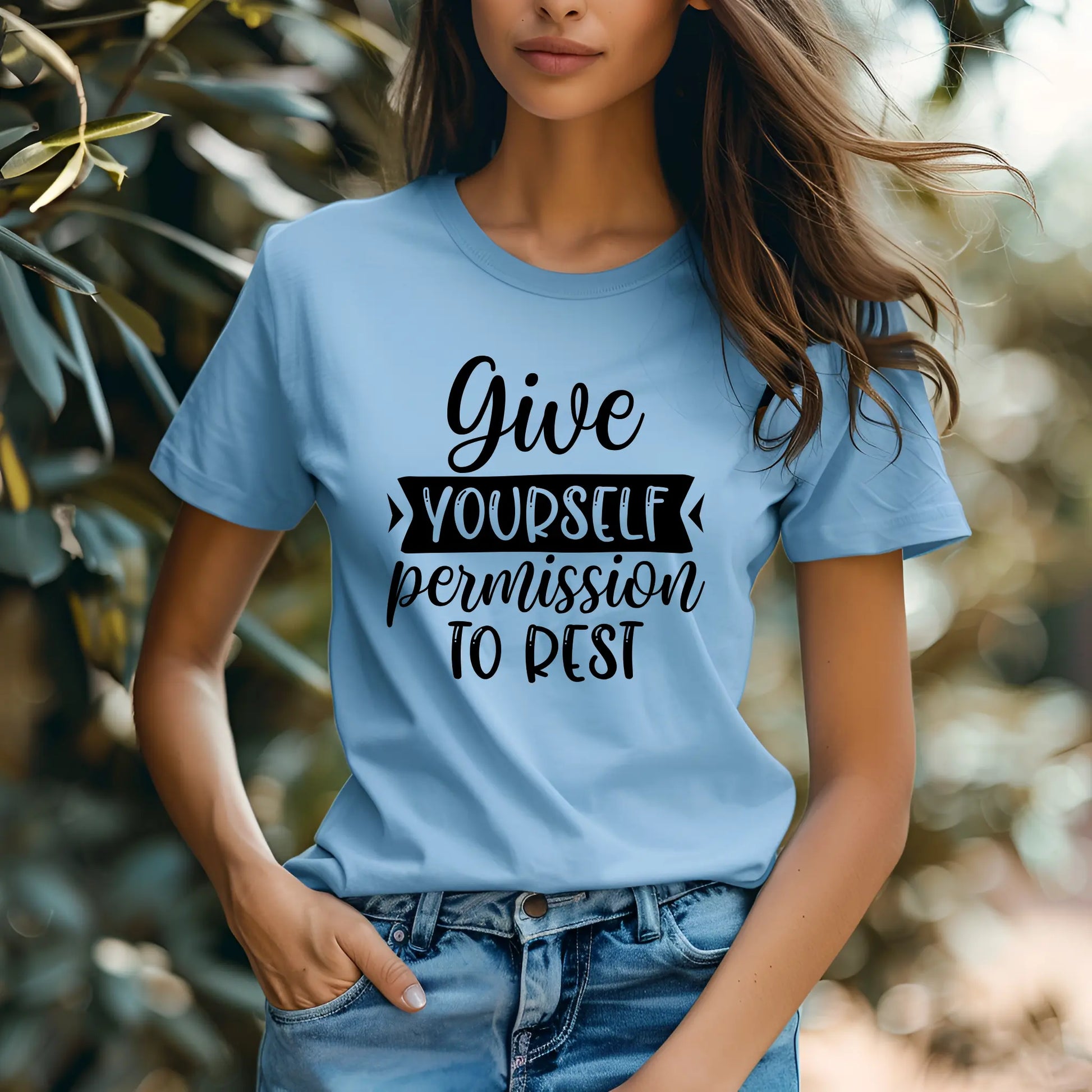 Person wearing a light blue t-shirt with motivational text in a natural setting