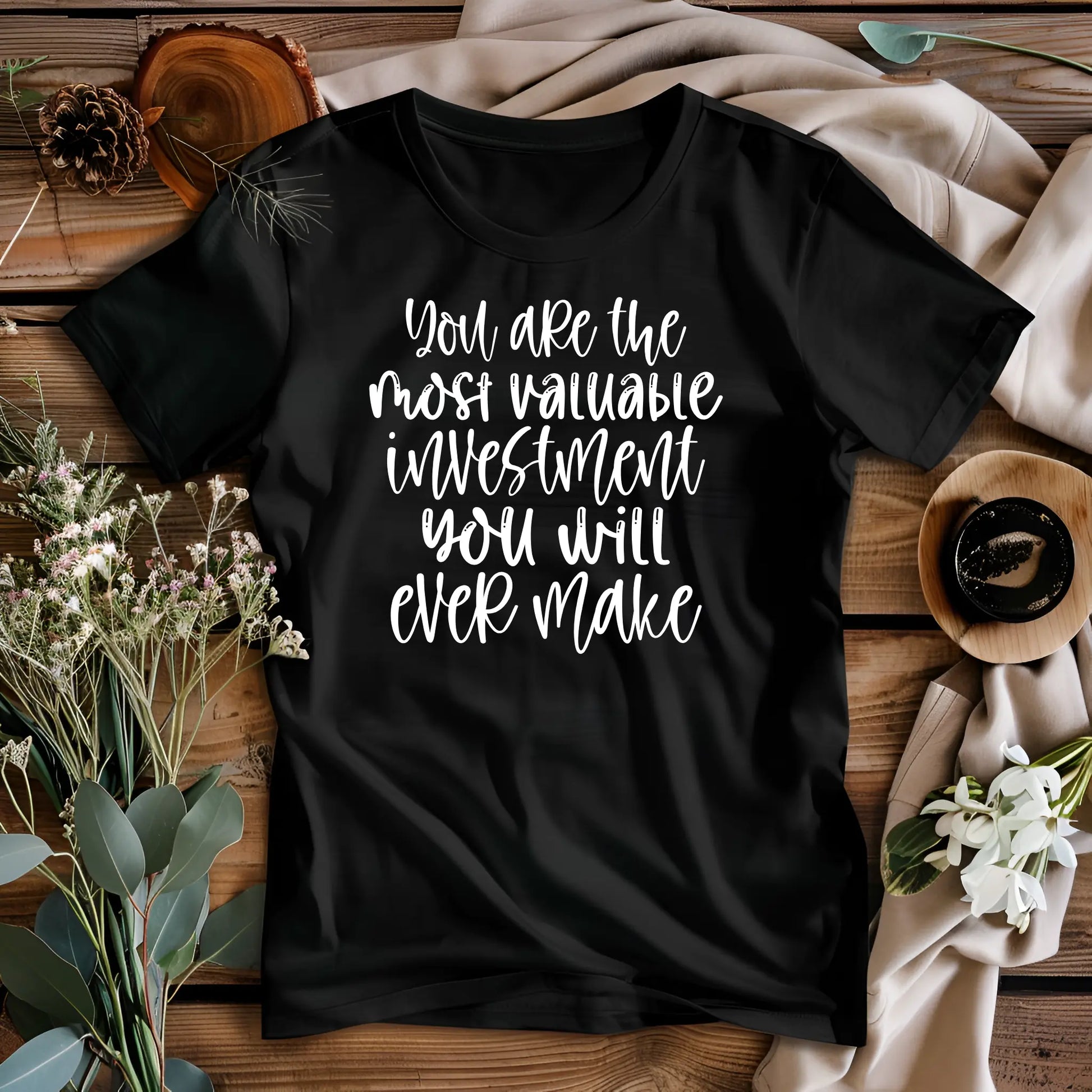 Black t-shirt with motivational quote on a wooden surface with decorative elements