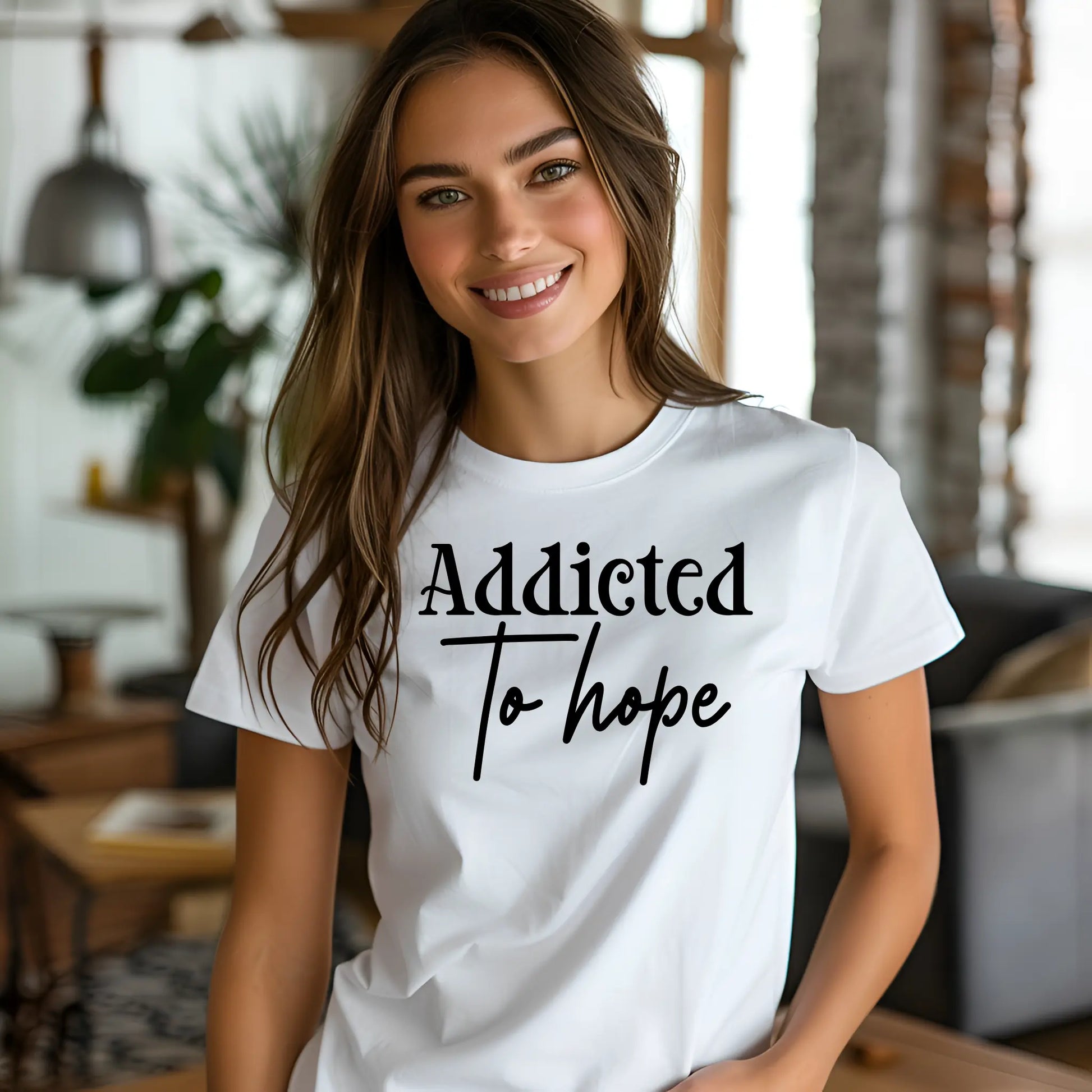 Woman wearing a white t-shirt with 'Addicted To Hope' text in a casual indoor setting.