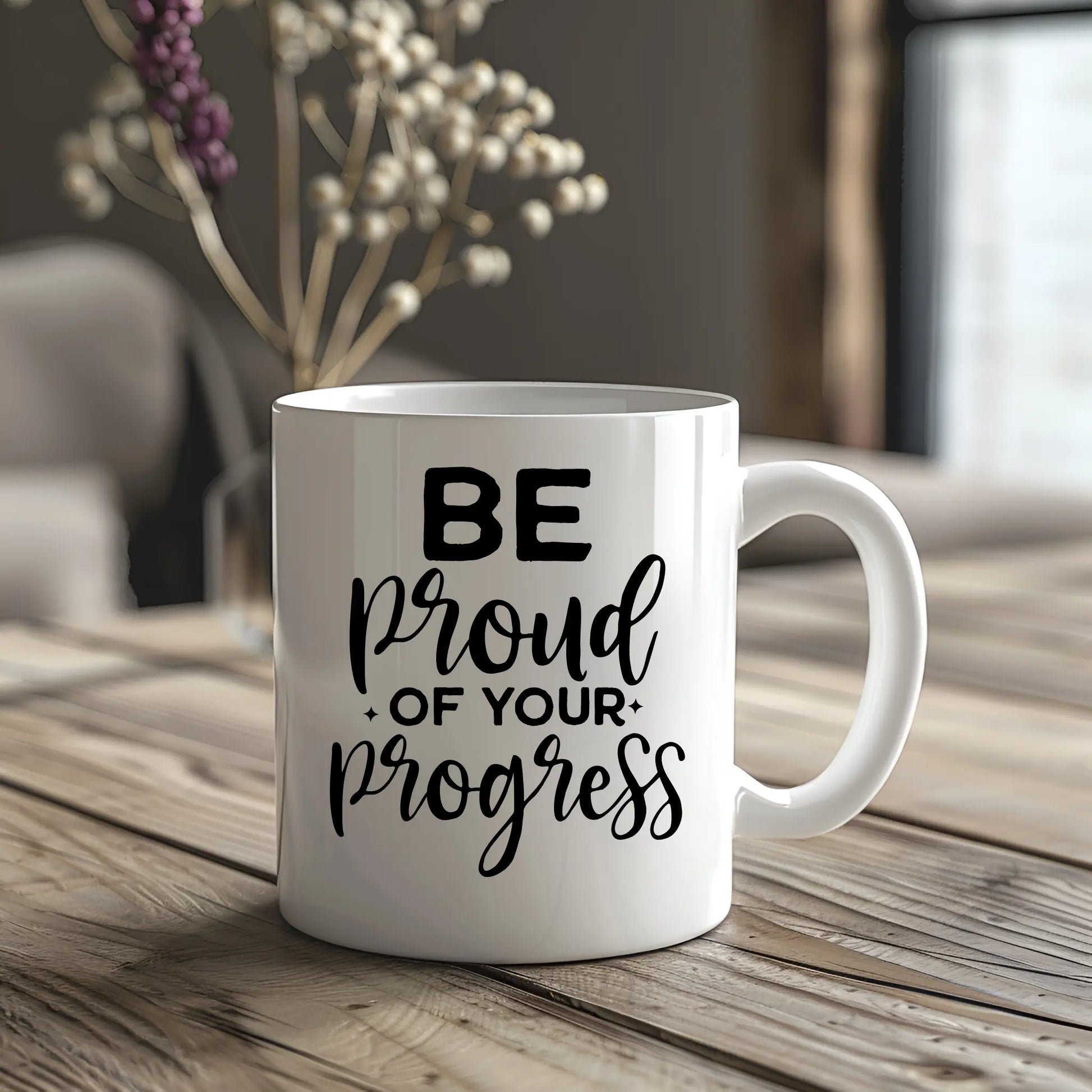 White mug with 'Be proud of your progress' text on a wooden table.