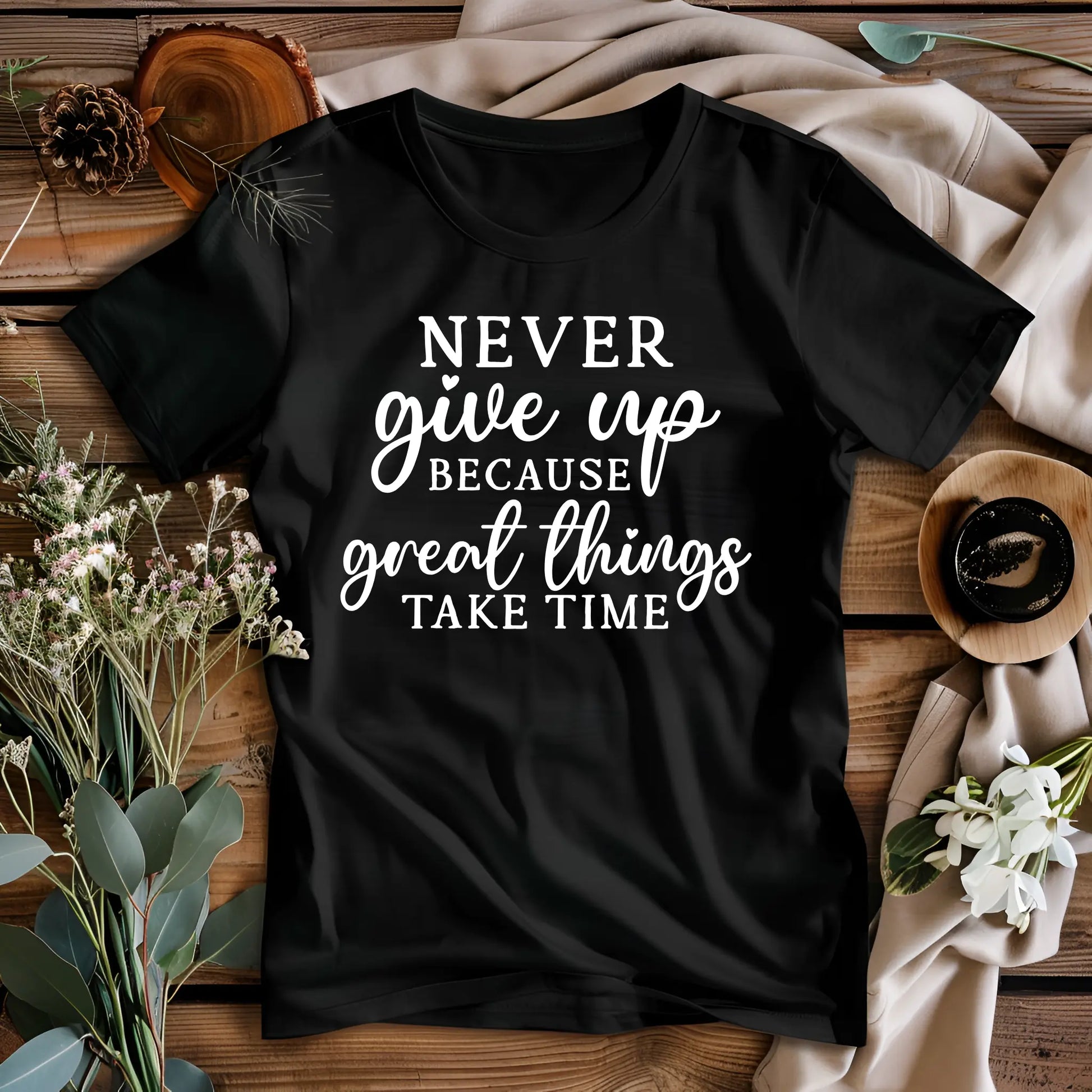 Black t-shirt with motivational quote on a wooden surface with decorative elements