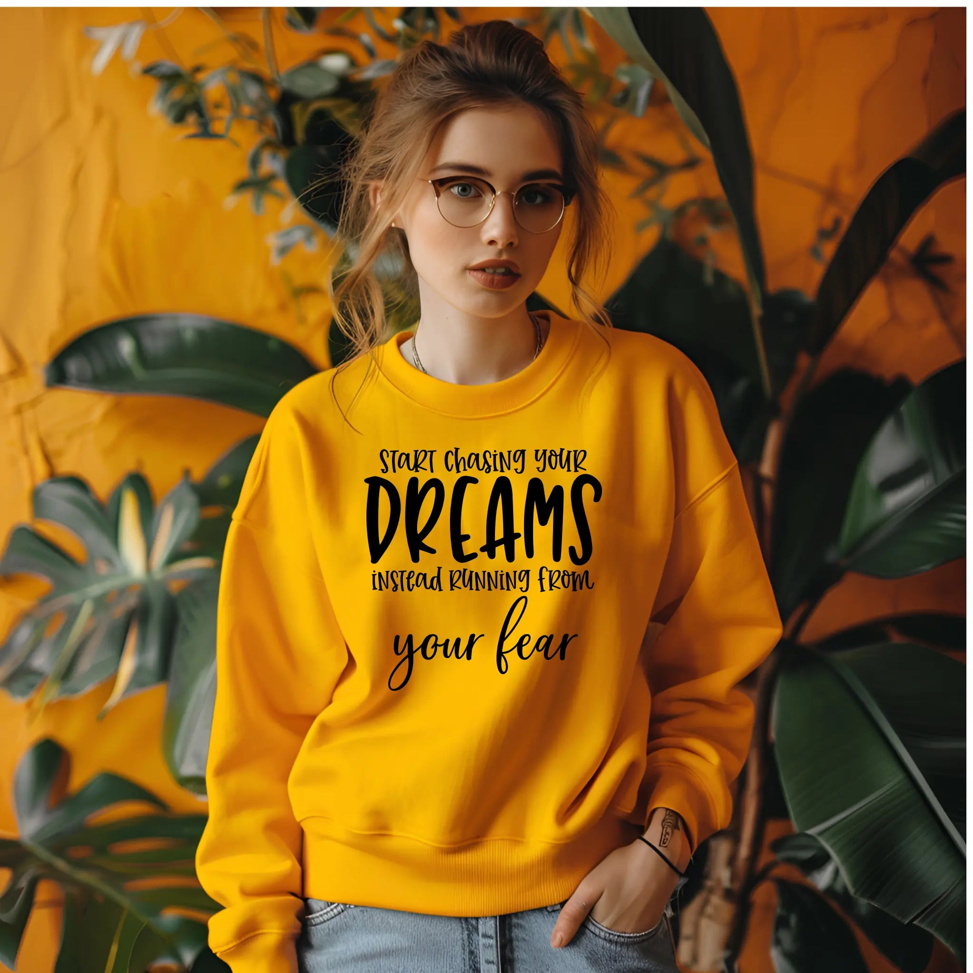 Woman wearing a yellow sweatshirt with motivational text against a plant-filled background