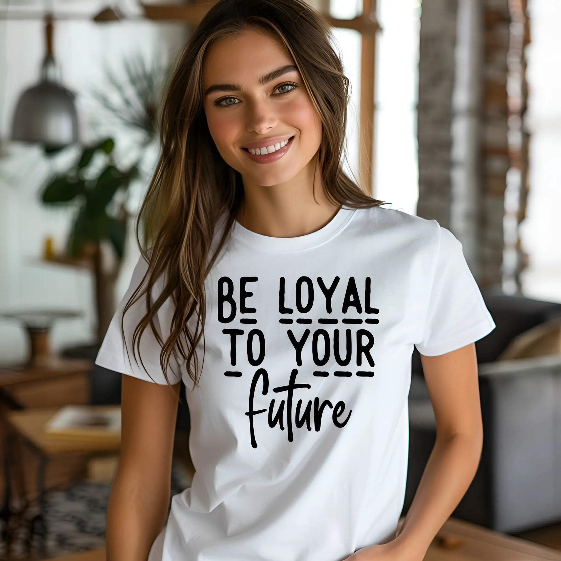 Woman wearing a white t-shirt with 'Be Loyal To Your Future' text in a casual indoor setting.