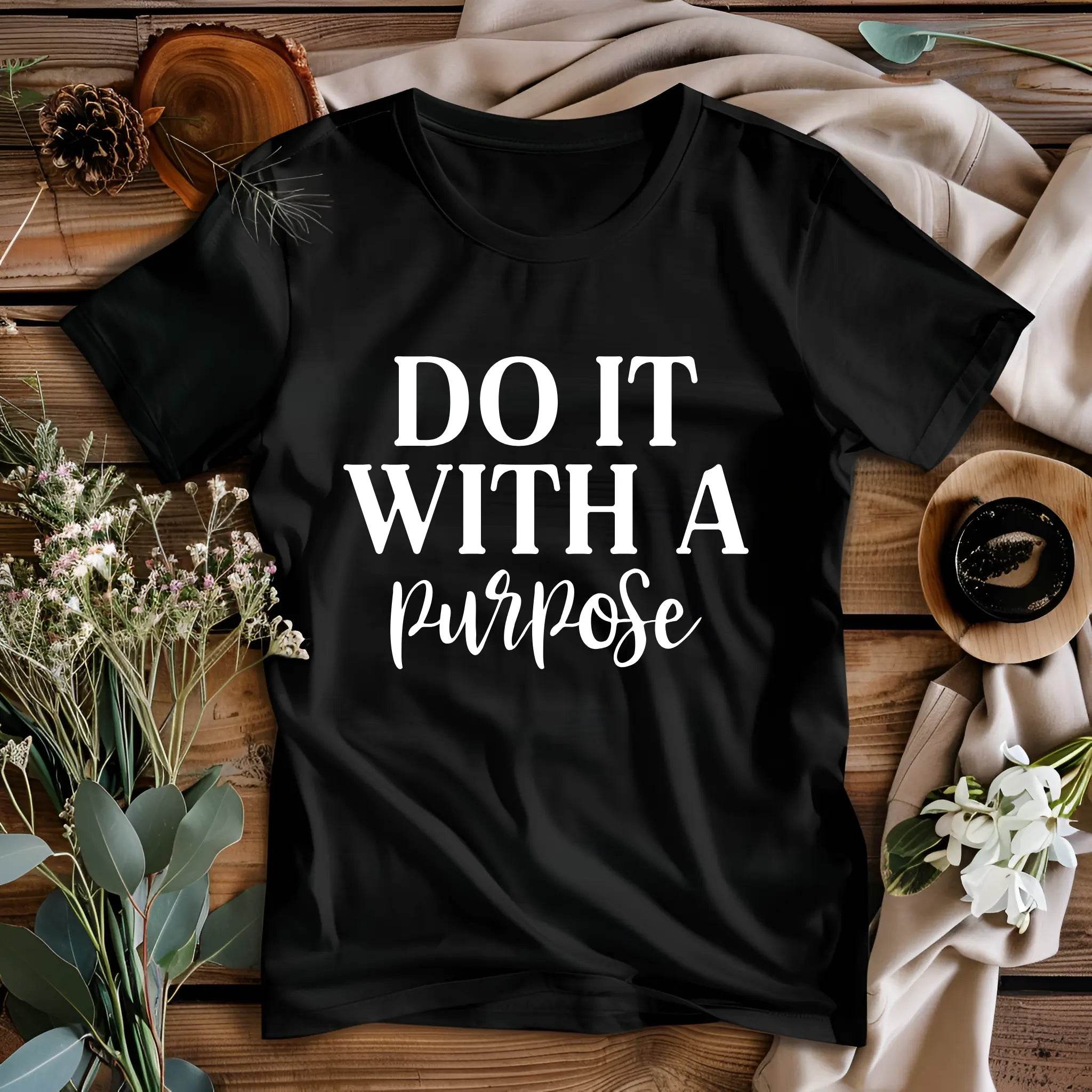 Black t-shirt with 'Do It With A Purpose' text on a wooden surface with decorative elements.