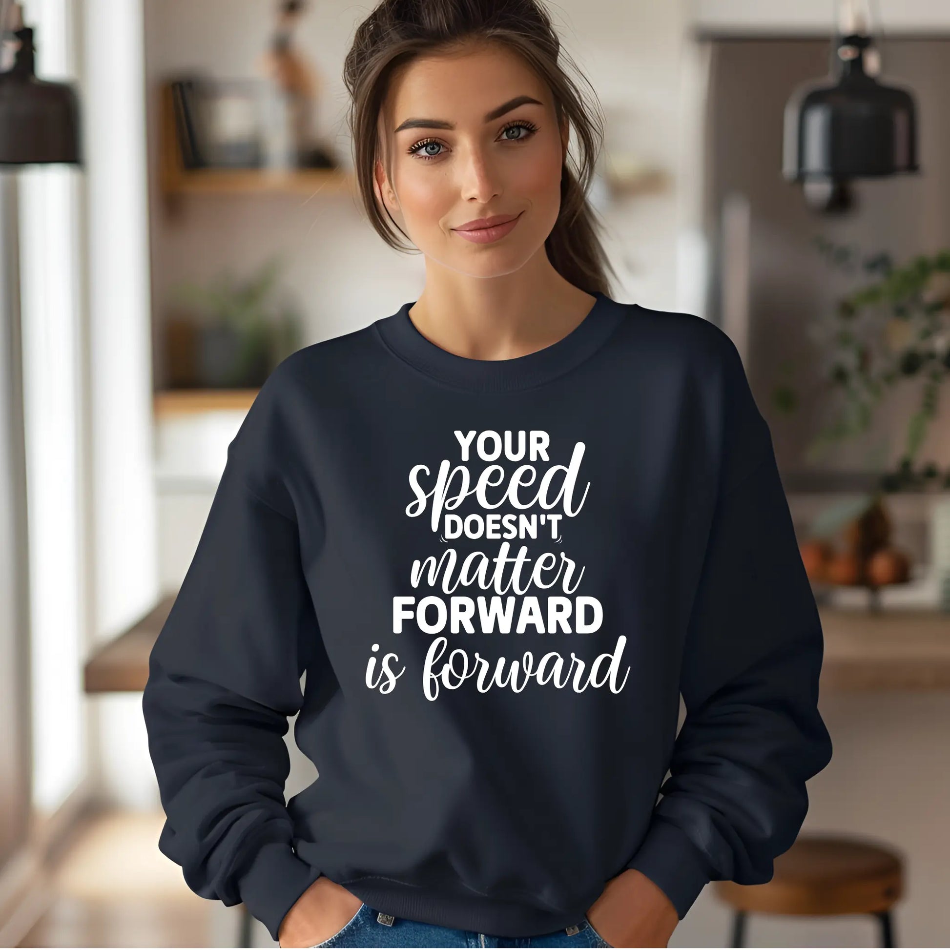 Woman wearing a navy sweatshirt with motivational quote in a blurred indoor setting
