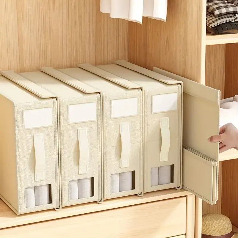 Beige storage bins with handles on a wooden shelf.