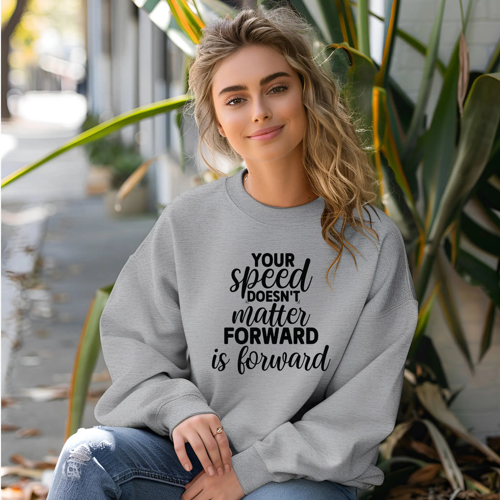 Woman wearing a gray sweatshirt with motivational text, sitting outdoors.