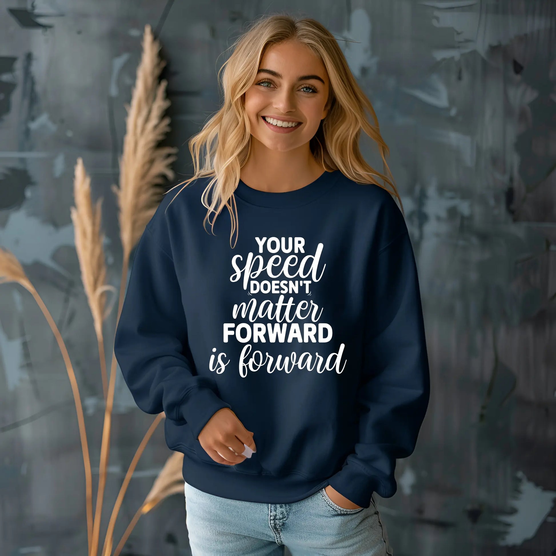 Person wearing a navy blue sweatshirt with motivational text, standing against a dark textured wall.