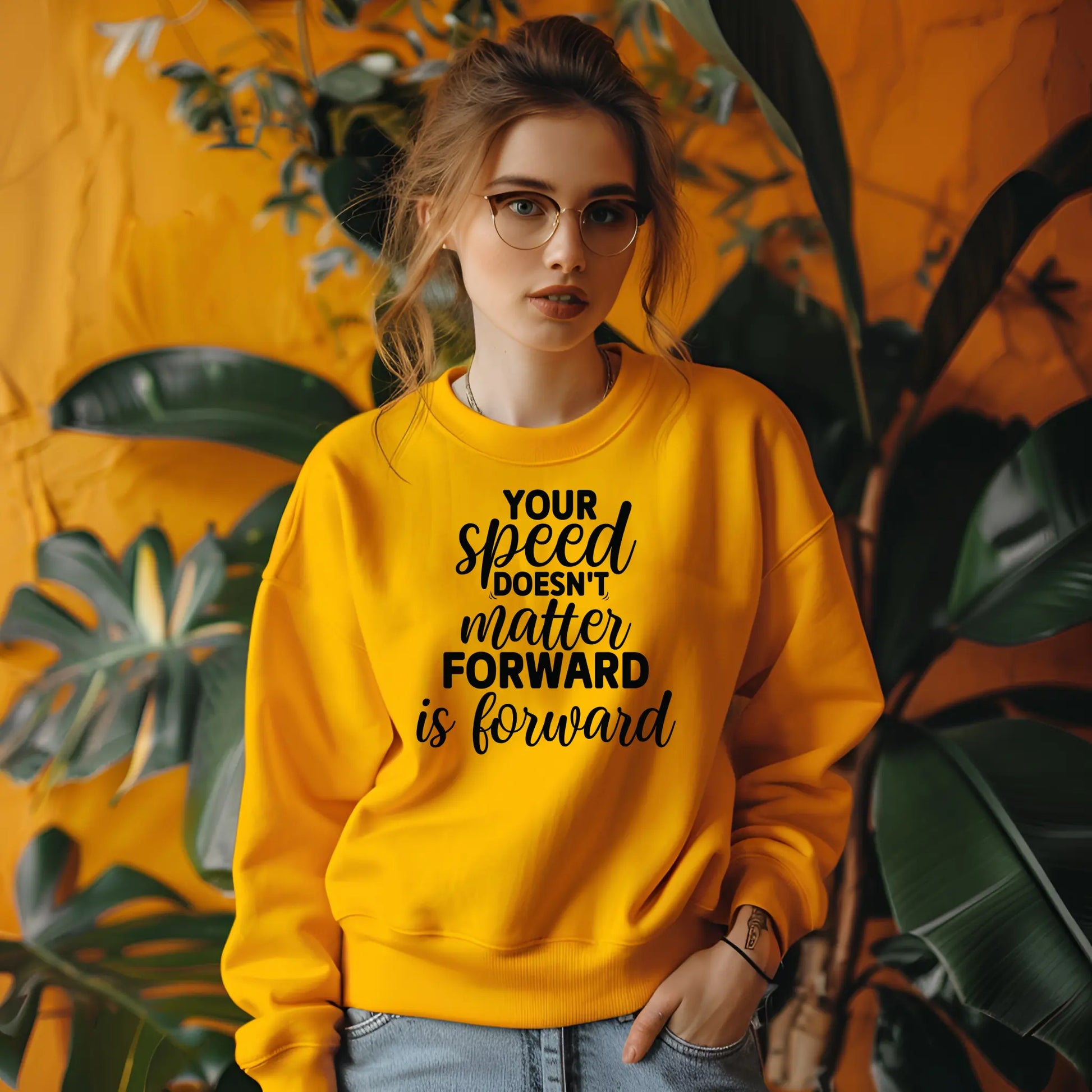 Person wearing a yellow sweatshirt with text in front of plants